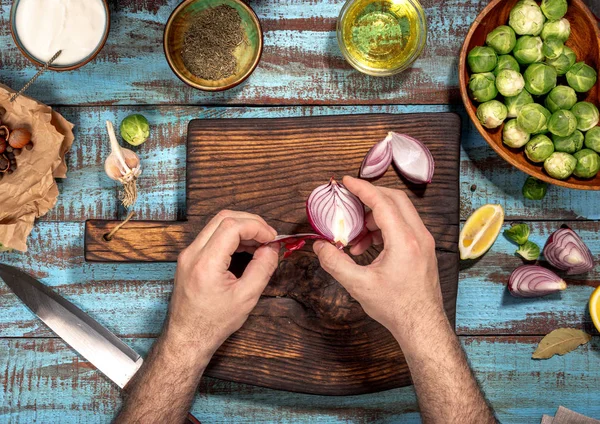 Человек готовит здоровую пищу брюссельской капусты на деревянном столе — стоковое фото