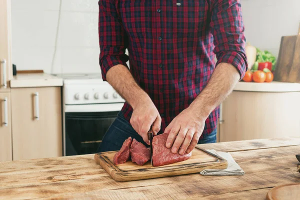 Człowiek kawałki mięsa wołowego na pokładzie cięcia drewnianych — Zdjęcie stockowe