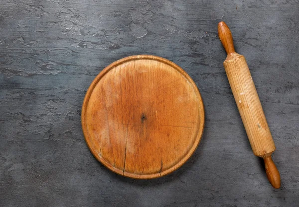 Tablero de madera con rodillo en la superficie de piedra oscura — Foto de Stock