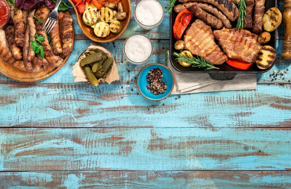 Diverse gegrilde voedsel op blauwe houten tafel met kopie ruimte — Stockfoto