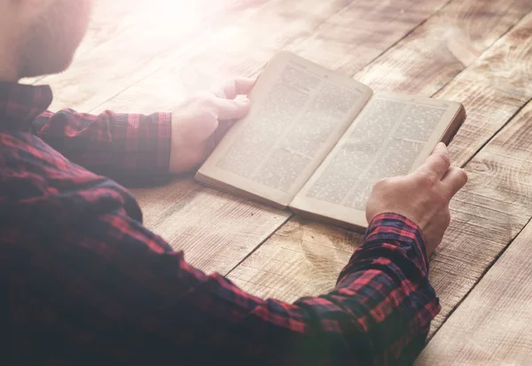 Homem leitura livro sentado em uma mesa de madeira — Fotografia de Stock