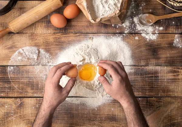 Manos masculinas batir la yema de huevo en la harina —  Fotos de Stock