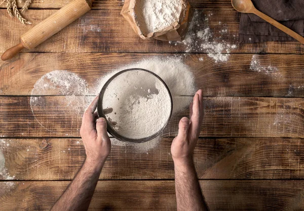 L'uomo ha setacciato la farina sul tavolo di legno — Foto Stock