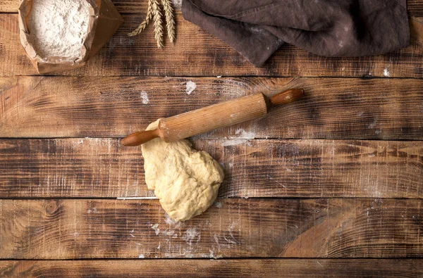 Fresh dough with rolling pin and flour on wooden table — Stock Photo, Image