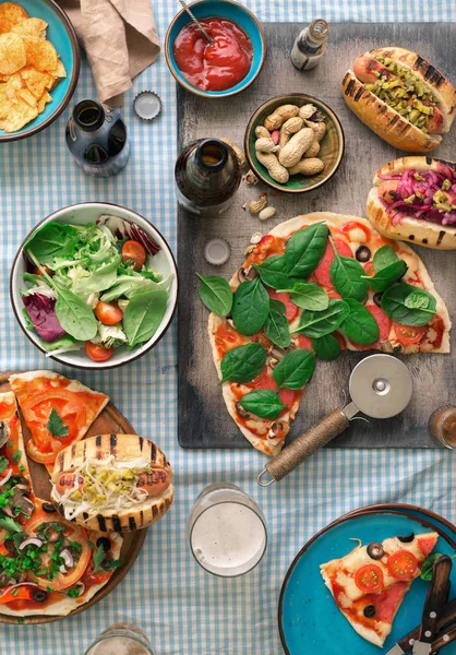 Pizza, cachorro-quente grelhado, salada, cerveja e lanches — Fotografia de Stock