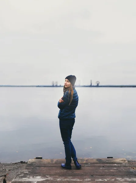 Молодая женщина, стоящая на деревянном пирсе на реке — стоковое фото