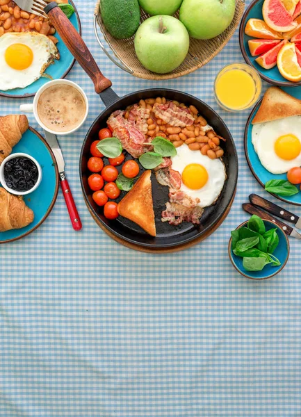 Sázené vejce, fazole, rajčata, slanina, toast různé ovoce, džus, — Stock fotografie