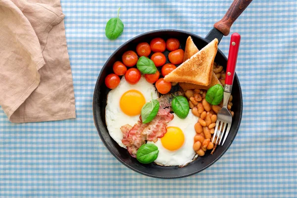 Gebakken ei, bonen, tomaten, spek en toast in de pan — Stockfoto