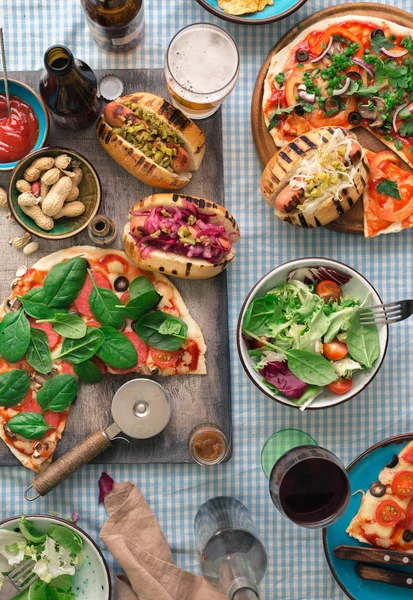 Varias pizzas caseras, diferentes hot dogs, vino, cerveza y snack — Foto de Stock