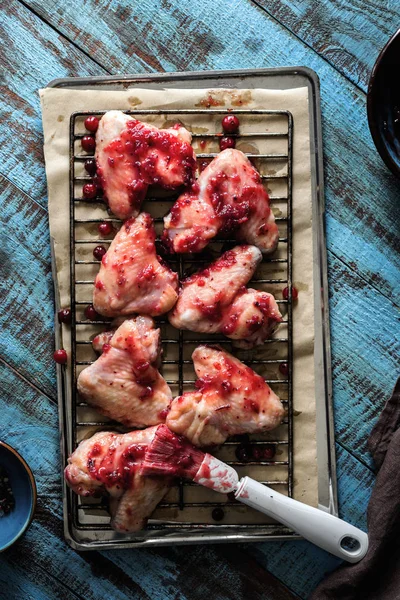 Raw chicken wings in cranberry sauce on baking sheet — Stock Photo, Image