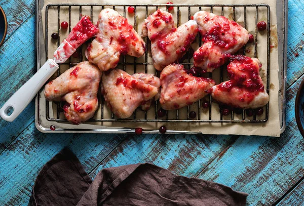 Close-up raw chicken wings in cranberry sauce on baking sheet — Stock Photo, Image