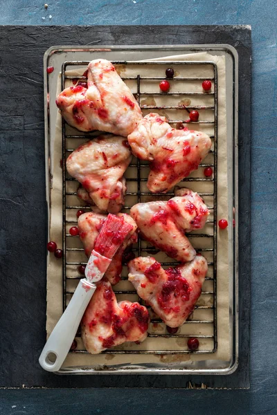 Raw chicken wings in cranberry sauce on dark stone surface — Stock Photo, Image