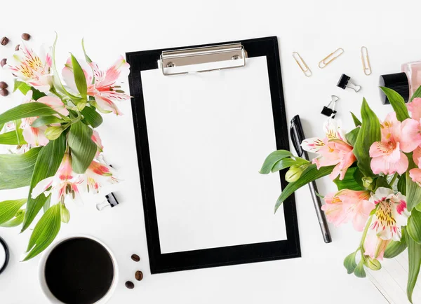 Espaço de trabalho com prancheta, acessórios de escritório, café e buquê — Fotografia de Stock