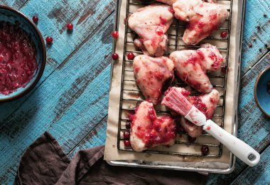 Mavi ahşap masa üzerinde kızılcık sosu tavuk kanatları