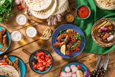 Yemek masası ile ızgara sosis, tortilla, bira ve farklı 