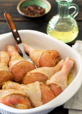 Ahşap masa üzerinde pişirme çanağı içinde çiğ tavuk budu