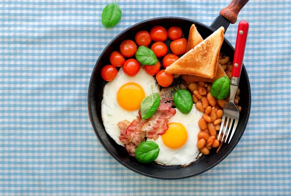 Table de petit déjeuner avec oeuf frit, haricots, tomates, bacon et pain grillé — Photo