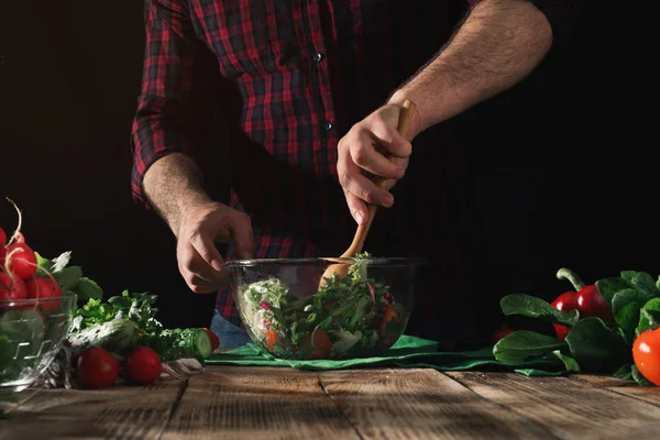 Человек перемешивает салат из свежих овощей — стоковое фото