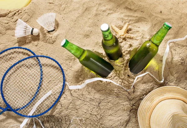 Bottles of cold light beer with items for beach entertainment
