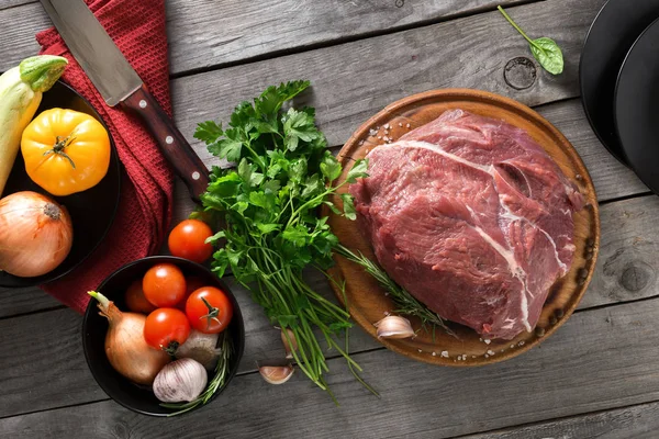 Fresh beef tenderloin on wooden table with different vegetables — Stock Photo, Image