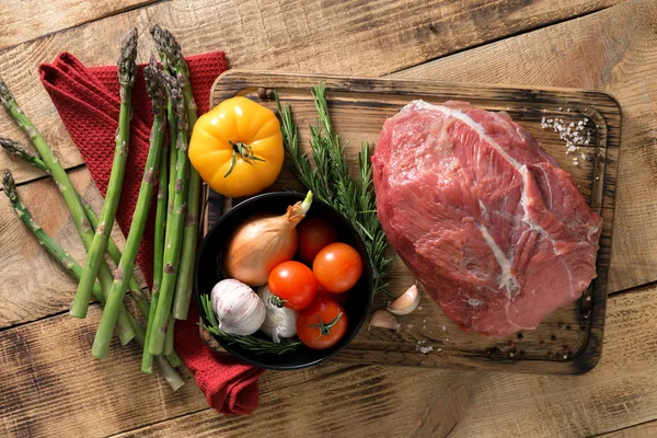 Fresh raw beef tenderloin with different vegetables on wooden ta — Stock Photo, Image