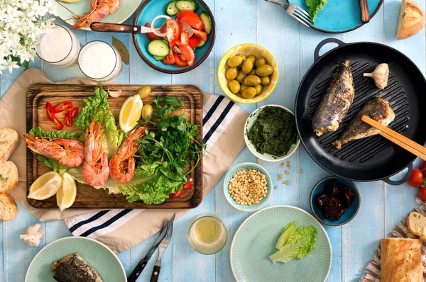 Dinner table with shrimp, fish grilled, salad, snacks and beer — Stock Photo, Image