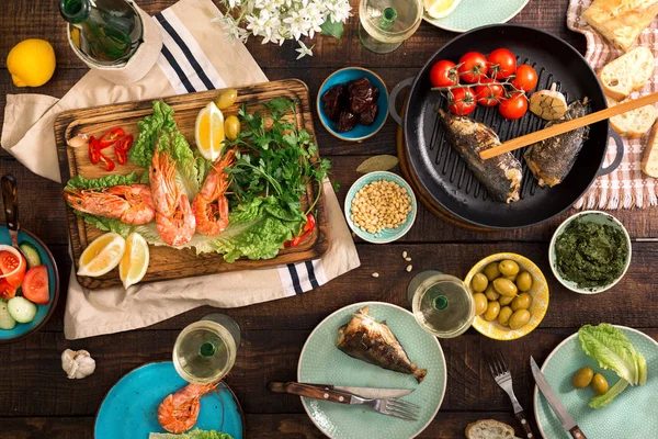 Обідній стіл з креветками, риба на грилі, салат, закуски та вино — стокове фото