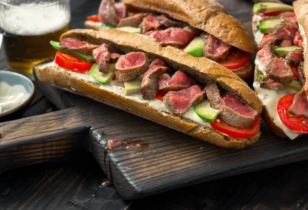 Sandwich with beef grilled on wooden board with beer — Stock Photo, Image