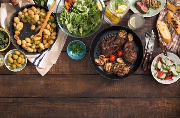 Eettafel met gegrilde biefstuk met groenten, aardappelen, salade, sn — Stockfoto