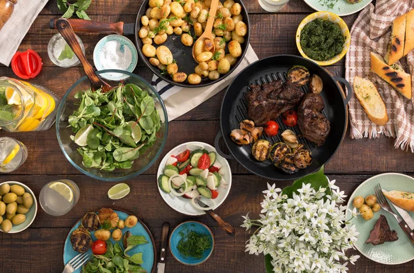 Обеденный стол с жареным стейком, овощами, картошкой, салатом, sn — стоковое фото
