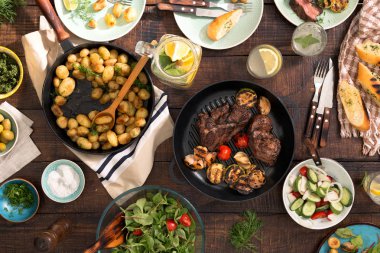 Yemek masası ile ızgara biftek, sebze, patates, salata, sn