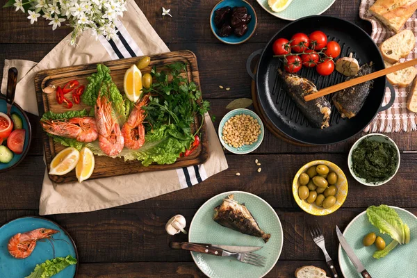 Tavolo da pranzo familiare con gamberetti, pesce alla griglia, insalata, diversi — Foto Stock