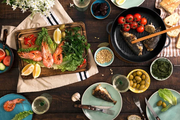 Mesa de cena con camarones, pescado a la parrilla, ensalada, aperitivos y vino — Foto de Stock