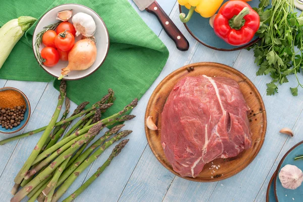 Fresh beef tenderloin with different vegetables on blue wooden t — Stock Photo, Image