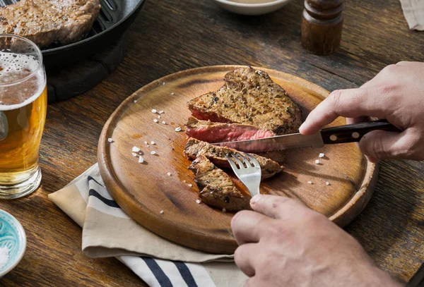 L'uomo sta cenando bistecca su un tavolo di legno rustico — Foto Stock