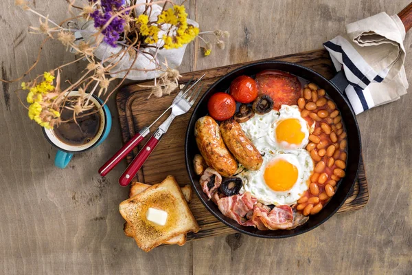 Café da manhã inglês em frigideira de ferro fundido com buquê de wildfl — Fotografia de Stock