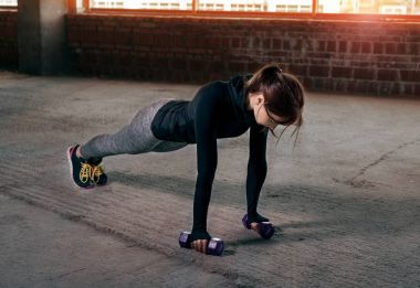 Kadın atlet push up yerdeki dumbbells ile