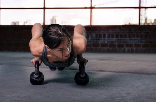 Mujer atleta flexiones con mancuernas en el suelo —  Fotos de Stock