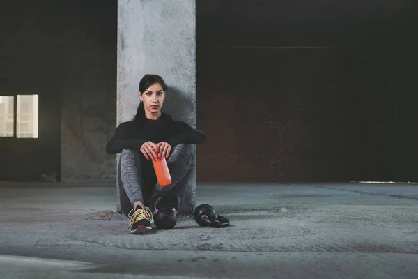 Mujer joven en ropa deportiva, sentada en el suelo después del entrenamiento — Foto de Stock