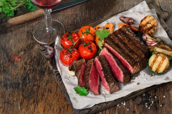 Plátky krvavý grilovaný steak s grilovanou zeleninou a červeným vínem — Stock fotografie