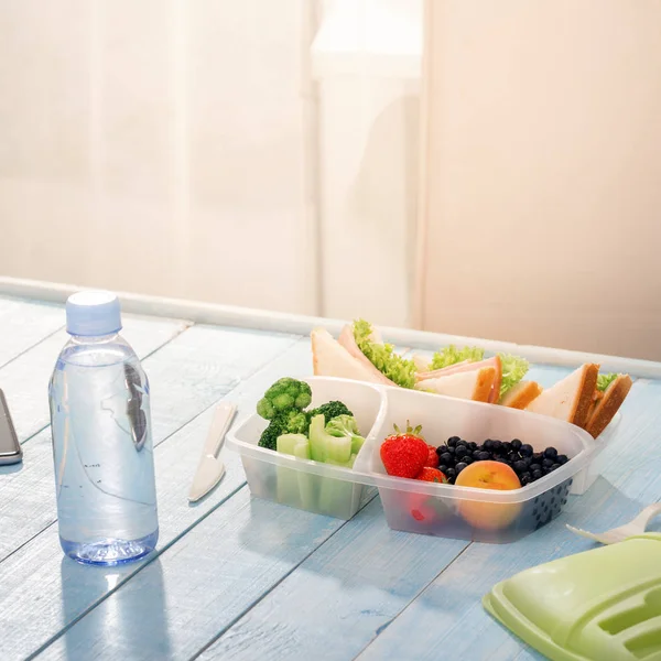 Lunch box with sandwich, vegetables, fruits and bottle of water — Stock Photo, Image