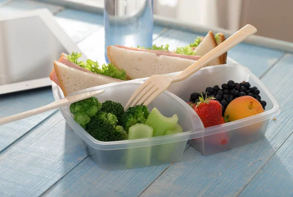 Boîte à lunch avec sandwich, légumes, fruits et bouteille d'eau — Photo