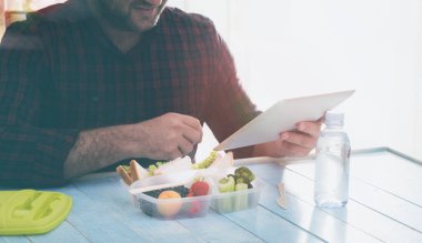 Tablet kullanma ve sağlıklı yemek yeme bir adam