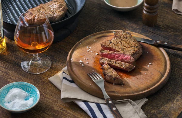 Carne de bovino bife grelhado raro em tábua de madeira com uísque — Fotografia de Stock