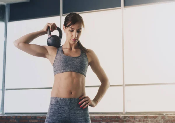 Woman athlete doing exercises with dumbbells in loft interior — Stock Photo, Image