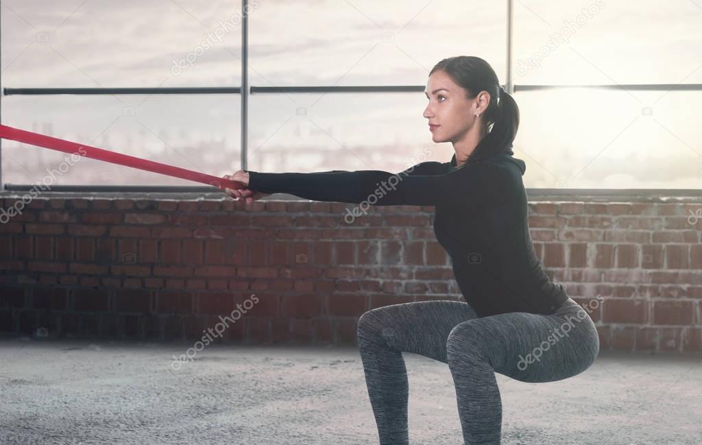 Woman athlete doing exercise with sports rubber. Copy space