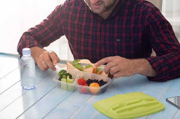 El hombre come sano almuerzo sentado en una mesa de madera —  Fotos de Stock