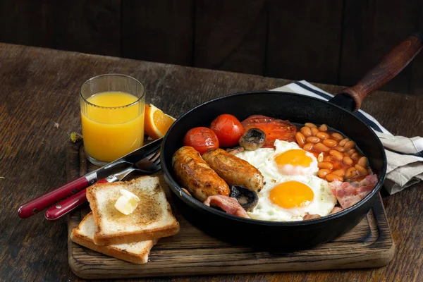 Полный английский завтрак на деревянном столе с апельсиновым соком — стоковое фото