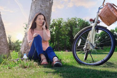 Gülümseyen kadın telefonda konuşuyor.