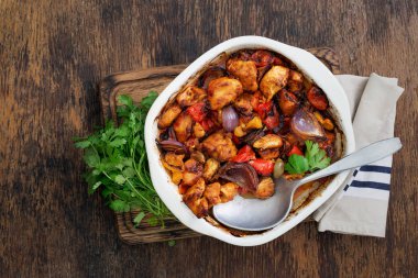 Karanlık rustik ahşap masa üzerinde sebzeli fırında tavuk göğsü